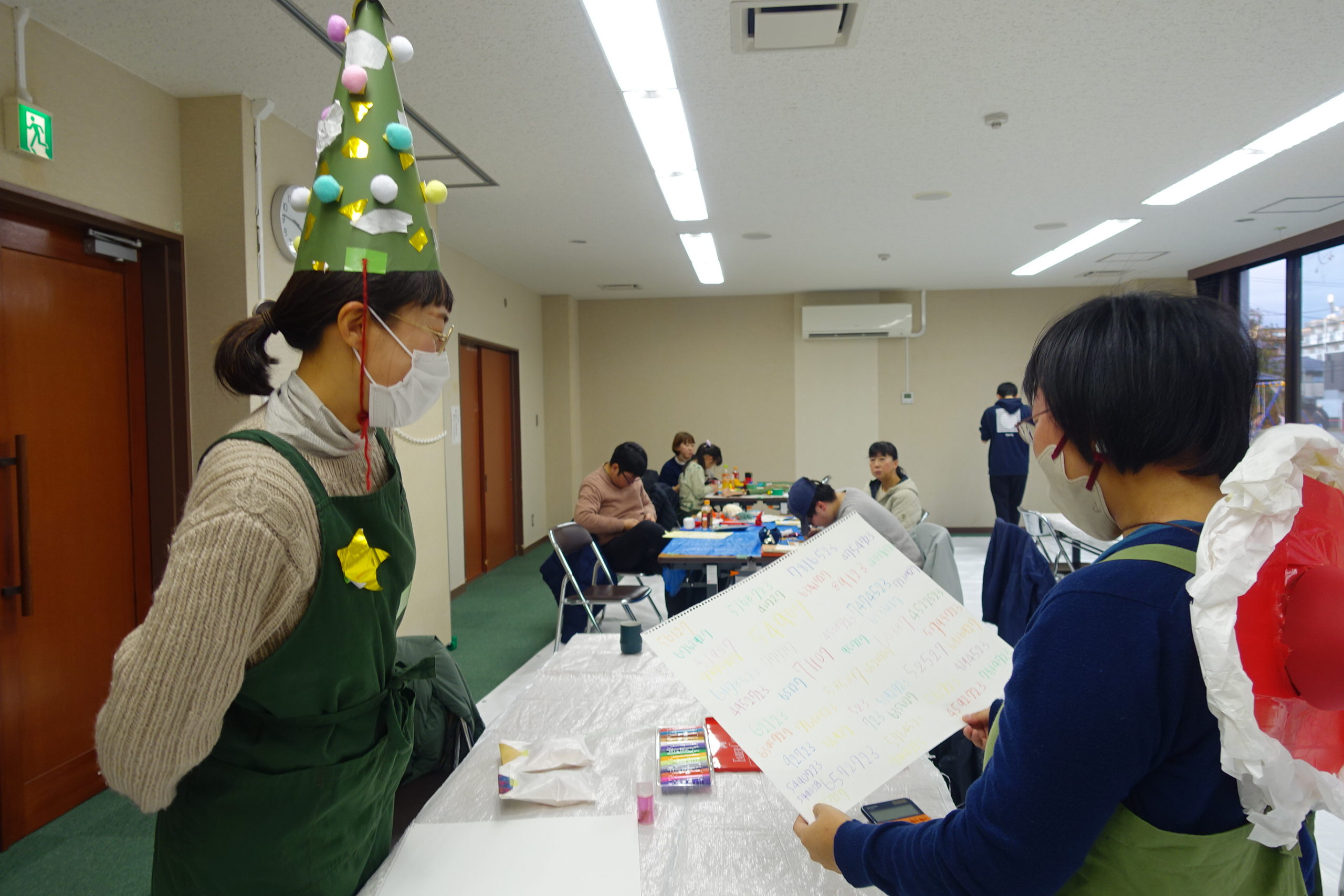 クリスマスツリーの形の帽子をかぶった門眞さんと、サンタクロースの赤い帽子を被った佐竹さん。どちらも画用紙の手作り。