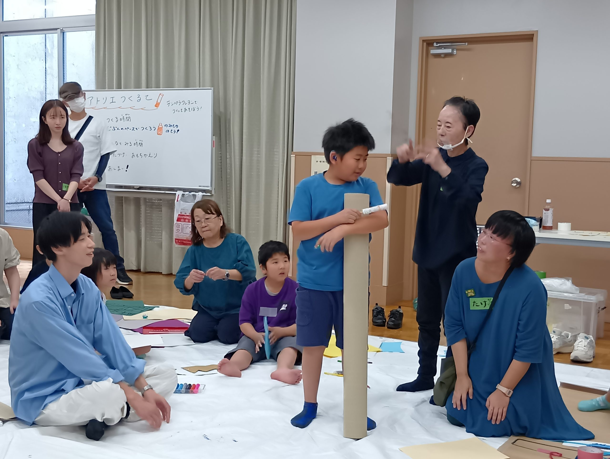 巻きダンボールを抱えた男の子の発表をまわりで子ども達やファシリテーターが笑顔で見守っている様子