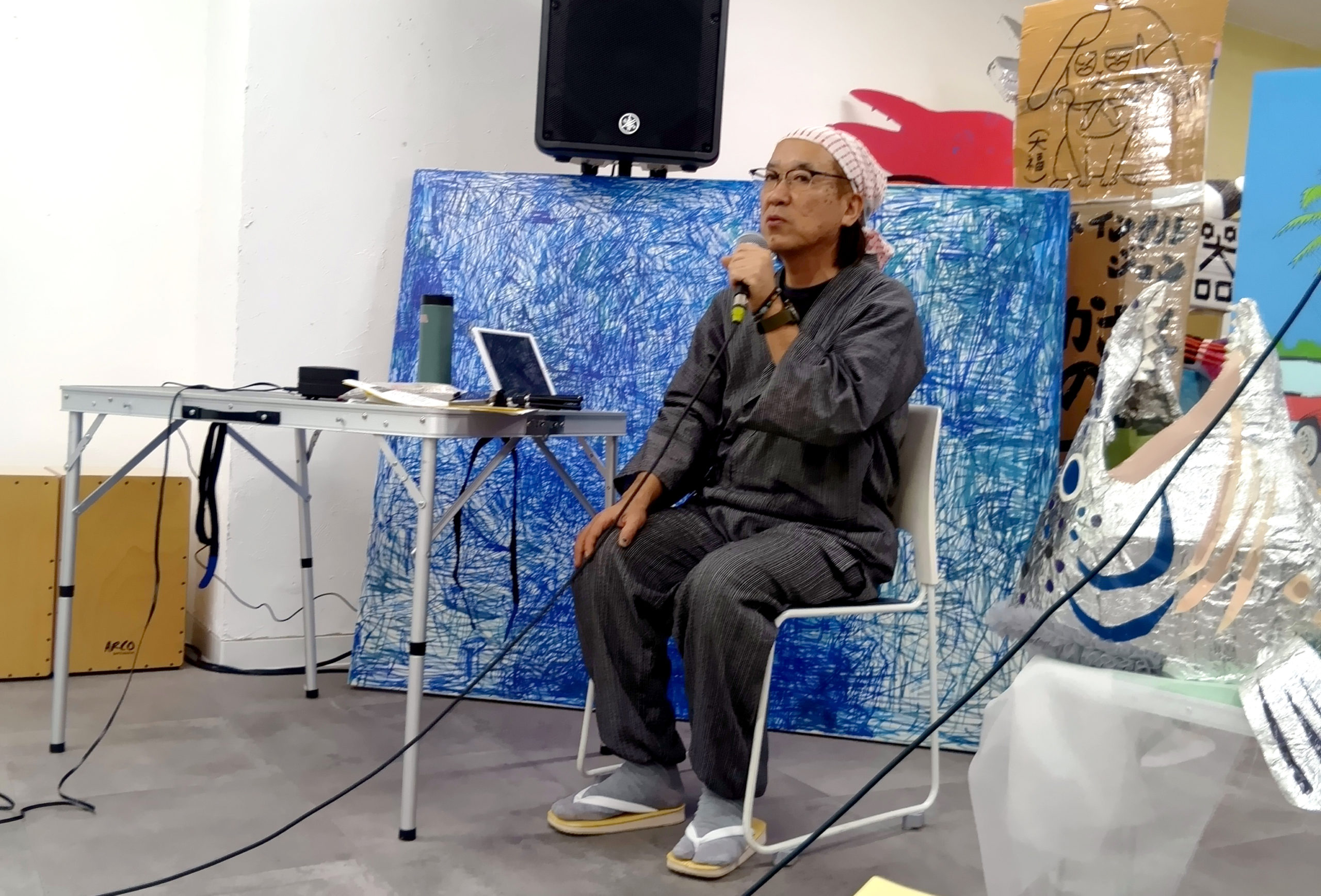 参加者のせこ三平さんがマイクで話す様子。せこさんは甚平を着用して頭にバンダナを巻いている。